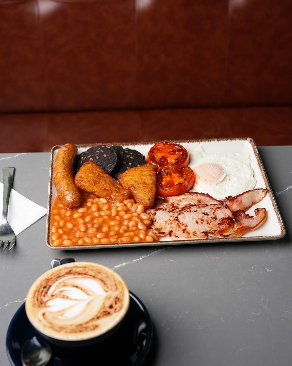 Full English breakfast with bacon, sausage, fried egg, black pudding, hash browns and beans, with a cappuccino, at Canons Cafe in Edgware