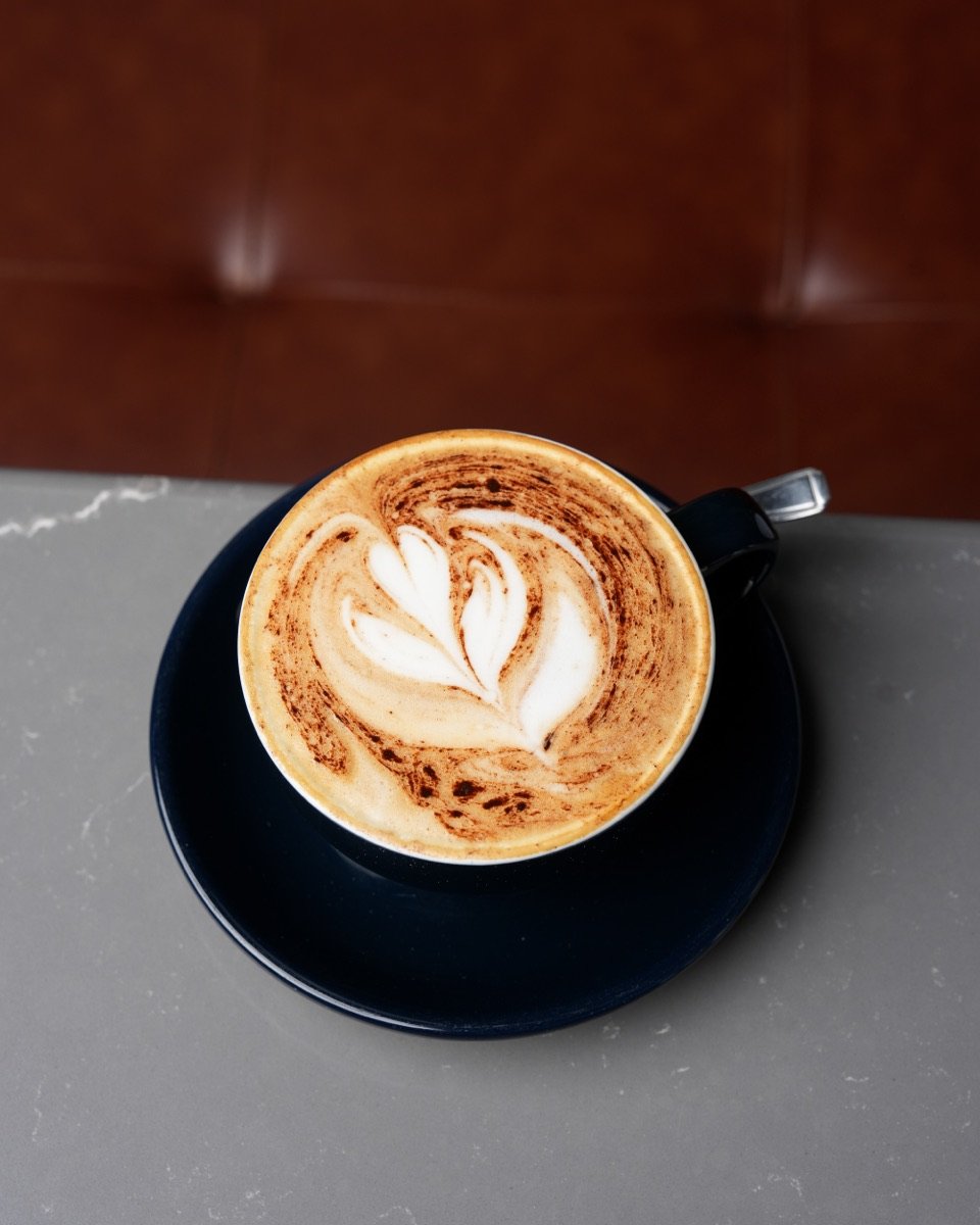 Cappuccino with heart latte art in a navy cup and saucer at Canons Cafe, Canons Park