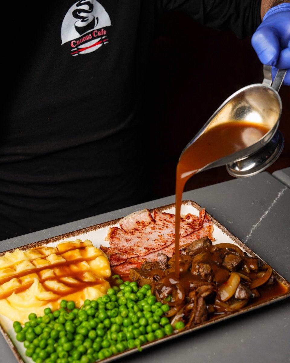 Chef at Canons Cafe pouring gravy over liver, bacon, mash and peas