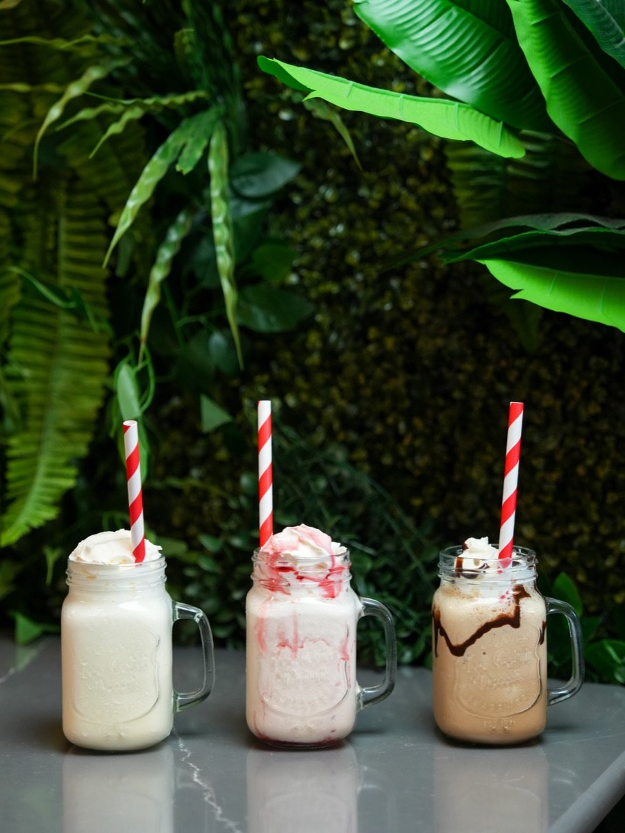 Three thick milkshakes in mason jars on the terrace at Canons Cafe, Canons Park